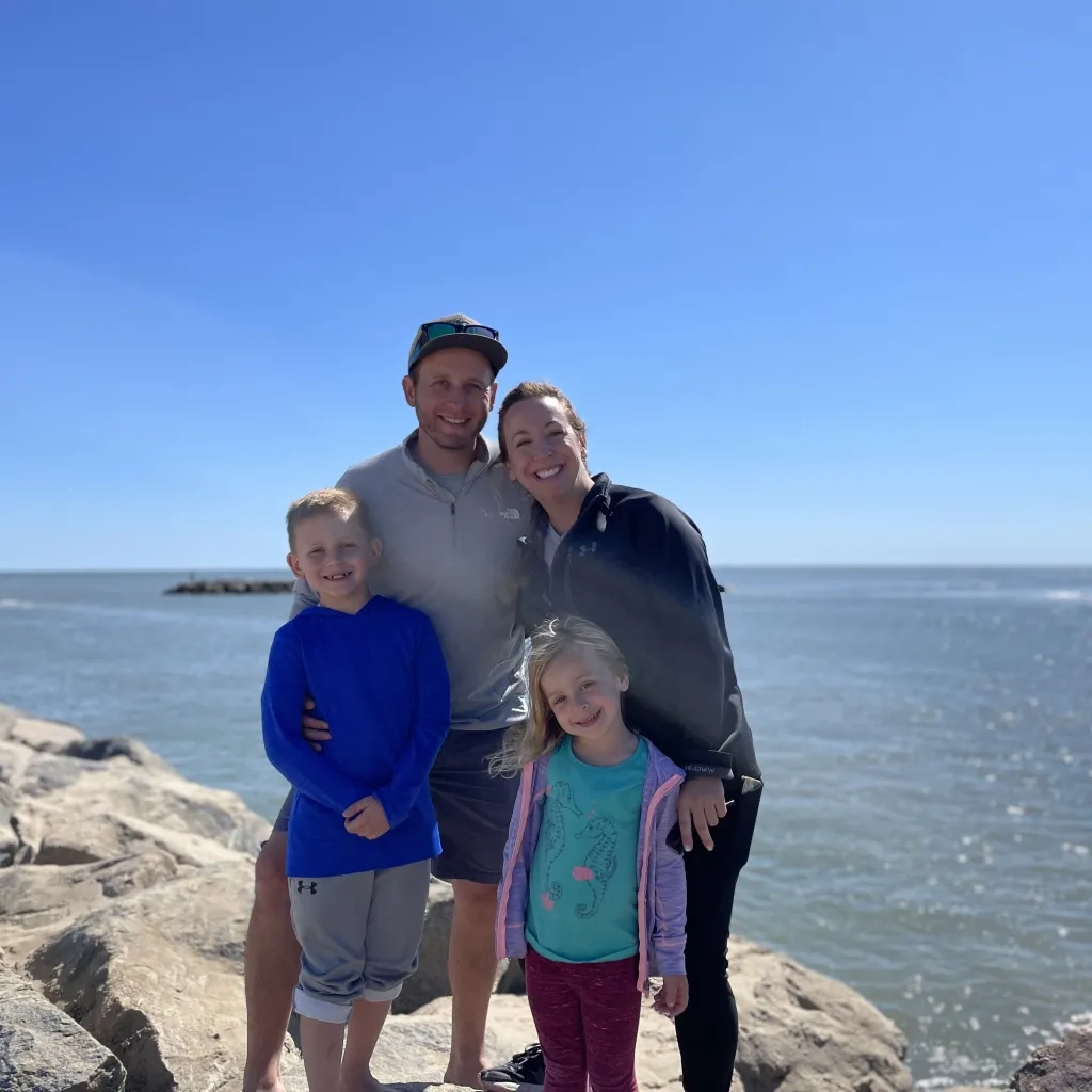 Dan Robb with his wife and two kids posing in front of ocean. 